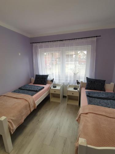 a bedroom with two beds and a window at Apartament nad wodą 2 in Marzęcino