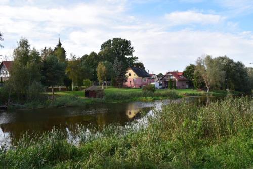 a river in a village with houses in the background at Apartament nad wodą 2 in Marzęcino