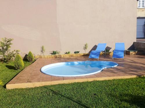 a swimming pool with two blue chairs and a patio at Charming House in Esteiro with Garden and Terraces in Esteiro