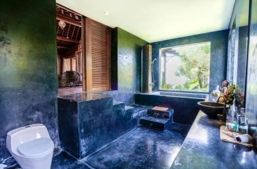 uma casa de banho azul com um WC e um lavatório em 4 bedrooms villa with sea view private pool and furnished garden at Kabupaten de Tabanan em Antasari