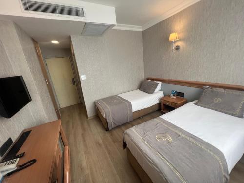 イスタンブールにあるFuar Hotelのベッド2台とテレビが備わるホテルルームです。