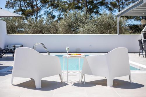 two white chairs and a table next to a pool at VillaPhysis with Private Pool in Lardos