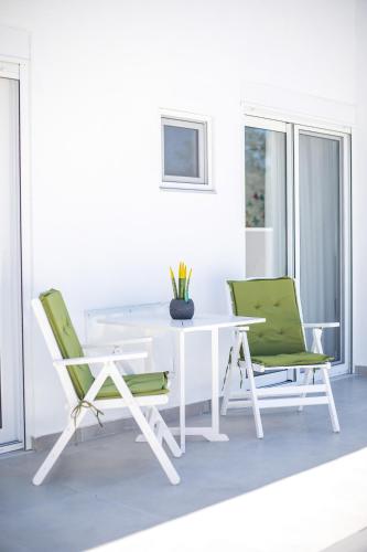 a white table and two green chairs in a room at VillaPhysis with Private Pool in Lardos