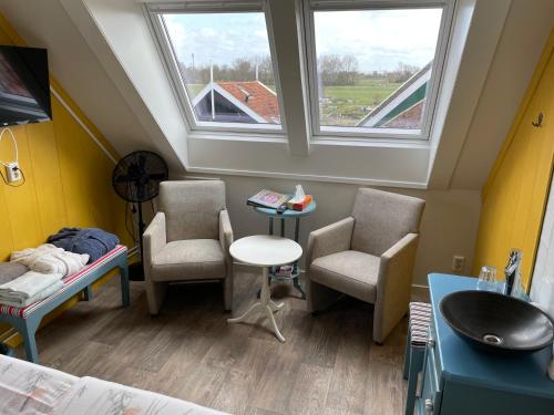 a room with two chairs and a table and two windows at Bed and Breakfast De Pepersteeg in Marken