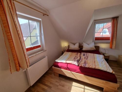 a small bedroom with a bed and two windows at Am Deich 22 Strandfalter Zingst in Zingst