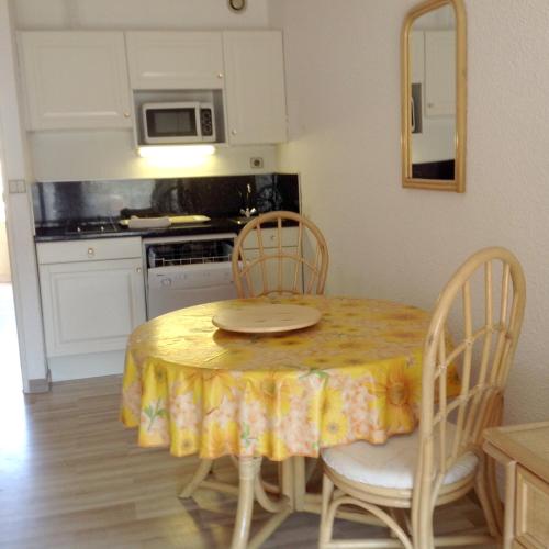 une cuisine avec une table et un chiffon de table jaune dans l'établissement Studio en bord de mer à Cavalaire-sur-Mer, 35 m², vue superbe., à Cavalaire-sur-Mer