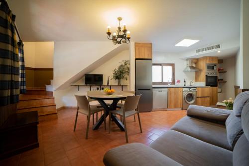 a living room with a dining room table and a kitchen at Casas Rurales Los Olivos in Alcalá del Júcar