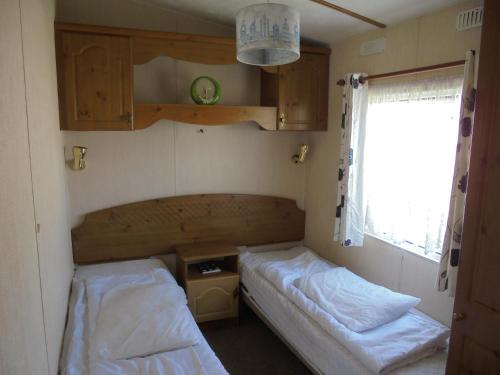 a small room with two beds and a window at 6 Berth on Golden Sands (Celebration) in Ingoldmells