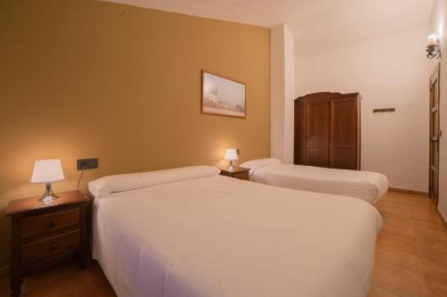 a hotel room with two beds and two lamps at Casas Rurales Los Olivos in Alcalá del Júcar