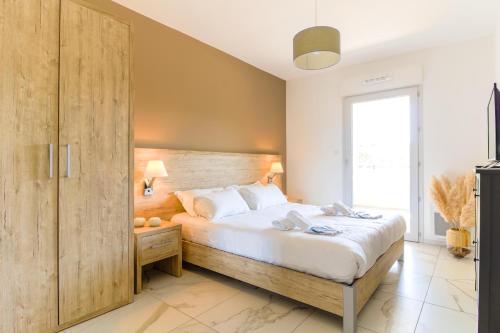 Schlafzimmer mit einem großen Bett mit einem Kopfteil aus Holz in der Unterkunft SELECT SO HOME - Magnifique appartement dans une résidence avec piscine et à proximité des plages - POS35 in Bormes-les-Mimosas