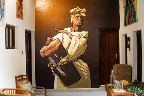 a wall with a painting of a man holding luggage at Tarawanda House by Stawi in Stone Town