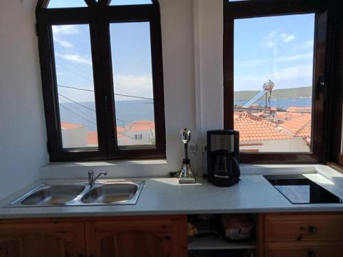 um balcão de cozinha com um lavatório e duas janelas em SIGRI'S BEAUTY em Sígrion