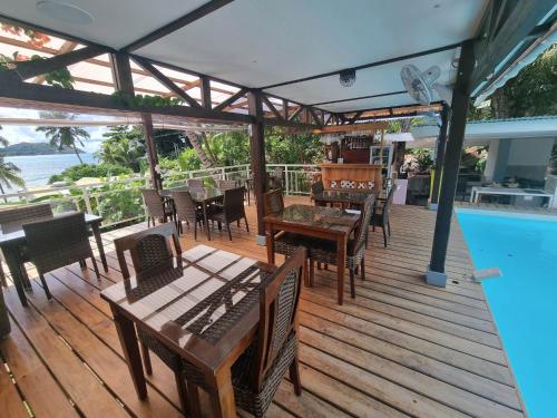 a wooden deck with tables and chairs next to a swimming pool at Mirella Villa Island Princess Villa in Praslin