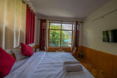 a bedroom with a large bed and a window at Urban Monk Stays and Cafe in Manāli