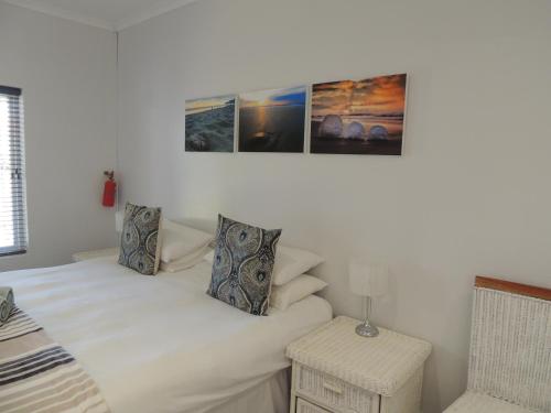 a bedroom with a bed and two pictures on the wall at Sand Dollar @ The Dunes in Plettenberg Bay