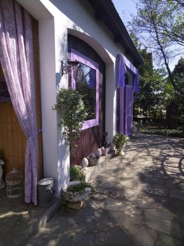 a white house with purple doors and potted plants at Cuore Verde in Cavour