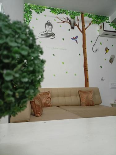 a living room with a couch and a tree on a wall at Leaf Garden Retreat in Varkala