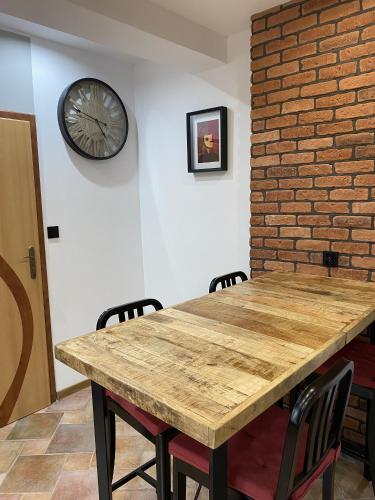 a wooden table with chairs and a clock on the wall at Gospodarstwo Agroturystyczne Zasadkowe Bory in Rogowo