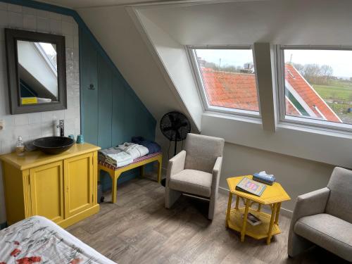 a attic room with a sink and a bed and two windows at Bed and Breakfast De Pepersteeg in Marken