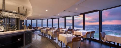a restaurant with white tables and chairs and windows at Hôtel Le Concorde Québec in Quebec City