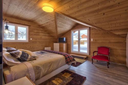 ein Schlafzimmer in einem Blockhaus mit einem Bett und einem roten Stuhl in der Unterkunft Chalet La Trinité-Spa,Sauna,Pétanque-Gérardmer in Gérardmer