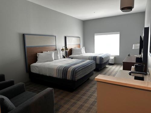 a hotel room with two beds and a chair at AmericInn by Wyndham Mountain Home in Mountain Home