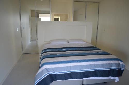 - une chambre dotée d'un lit avec une couverture rayée bleue et blanche dans l'établissement Koopalanda Dreaming, à Vivonne Bay