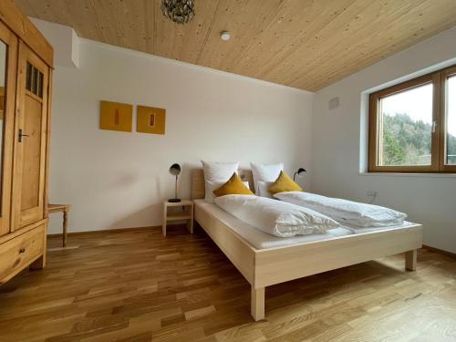 - une chambre avec un lit doté de draps blancs et d'oreillers jaunes dans l'établissement Gamsfels Josephine Galeriewohnung, à Langen bei Bregenz