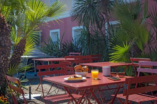 a picnic table with a plate of food and orange juice at Ibis Budget Fréjus Capitou in Fréjus