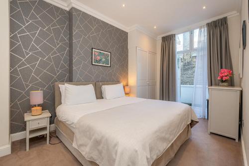 Un dormitorio con una gran cama blanca y una ventana en Manson Place, en Londres