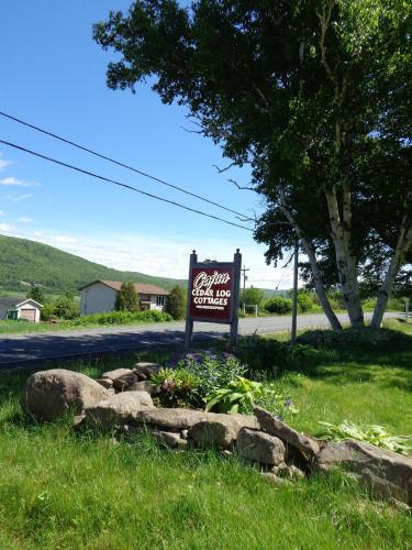 a sign in the grass next to a street at Cajun Cedar Log Cottages in Margaree Forks