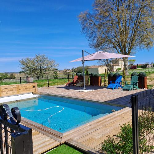 une piscine avec une terrasse en bois et un parasol dans l'établissement La Chartreuse d'Ertan 