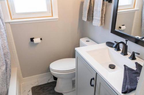 a bathroom with a white toilet and a sink at The Harperwood's Haven in Harper Woods