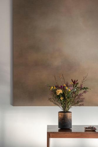 a vase of flowers on a table in front of a painting at L'AND Vineyards - Relais & Châteaux in Montemor-o-Novo