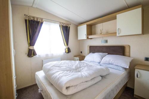 a bedroom with a large white bed with a window at Brilliant 8 Berth Caravan At Haven Caister Holiday Park In Norfolk Ref 30024d in Great Yarmouth