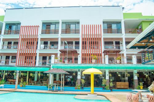 a large building with a pool and a yellow umbrella at Moalboal Tropics in Moalboal