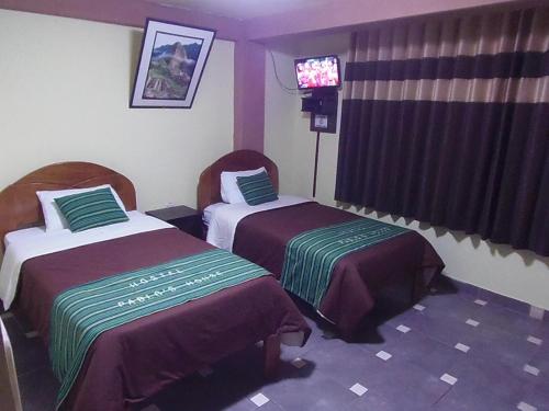 una camera d'albergo con due letti e una televisione di Hostal Pablo's House a Machu Picchu