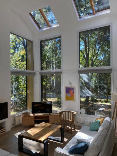 Casa del Bosque في سان كارلوس دي باريلوتشي: غرفة معيشة مع نوافذ كبيرة وأريكة بيضاء