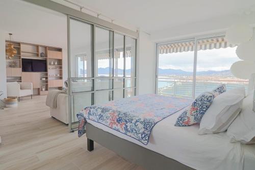 um quarto com uma cama e uma grande janela em LE MEDITERRANEEN - Renovated apartment with sea view em Cannes