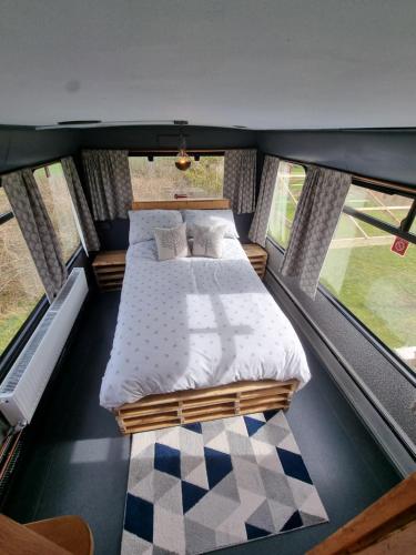 a large bed in a room with windows at Dawel Nos Glamping in Sarnau