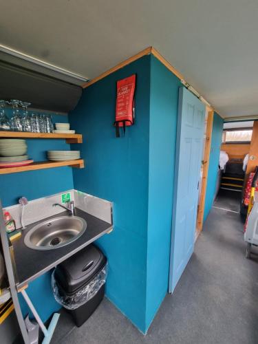 a bathroom with a sink and a blue wall at Dawel Nos Glamping in Sarnau