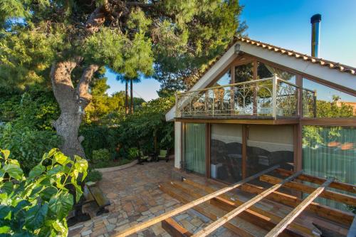 a house with a deck and a tree at Turdus Merula Retreat in Nea Makri