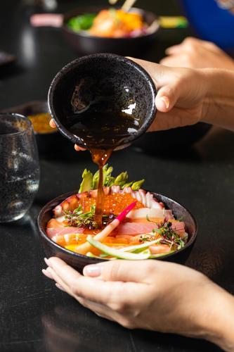 a person pouring sauce into a bowl of food at Dusit Thani Dubai in Dubai