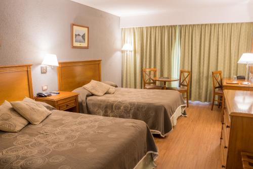 Cette chambre d'hôtel comprend deux lits, une table et des chaises. dans l'établissement Howard Johnson Rio Cuarto Hotel y Casino, à Río Cuarto