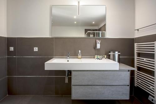 łazienka z białą umywalką i lustrem w obiekcie Villa Ryx avec piscine w mieście Grimaud