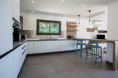 a kitchen with white cabinets and a counter with stools at Villa Ryx avec piscine in Grimaud