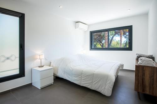 a white bedroom with a bed and a window at Villa Ryx in Grimaud