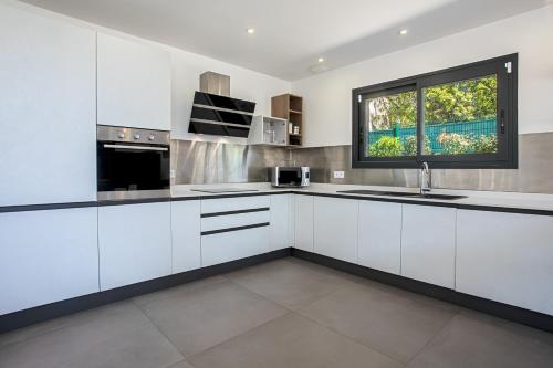 a kitchen with white cabinets and a window at Villa Ryx avec piscine in Grimaud