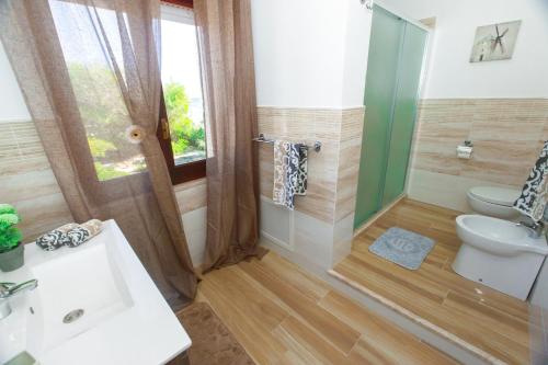baño con lavabo y aseo y ventana en Villa Blue Sea - Xenia Sicily Villas, en Mazara del Vallo
