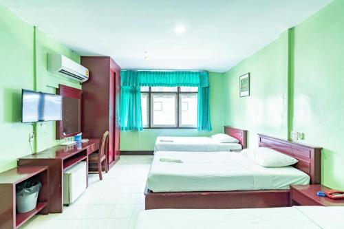a hotel room with two beds and a television at Woodlands Inn in Bangkok